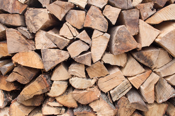 Background of chopped firewood stacked up on top of each other in a pile