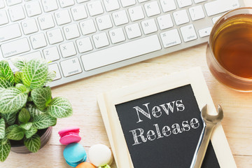 Concept News Release message on wood boards. Macaroons and glass Tea on table. Vintage tone.