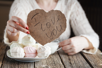 Woman holding paper heart while eating sweets
