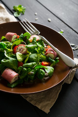Fresh vegetable salad with rolls of ham and cheese