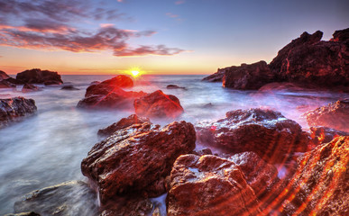 Fototapeta na wymiar Beautiful sunrise on rocky shore and dramatic sky clouds