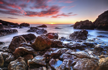 Beautiful sunrise on rocky shore and dramatic sky clouds