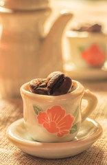 Coffee beans in a small lovely porcelain cups close-up. Strong coffee poster. Creative cozy design.
