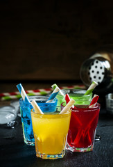, yellow, red and green alcoholic cocktails with striped straws,