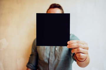 Young man showing a square black blank page on a white background