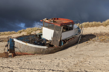 Fototapeta premium Abandoned and wrecked old fishing boat at the mouth of River Wansbeck, on the coast of Northumberland, England, UK.