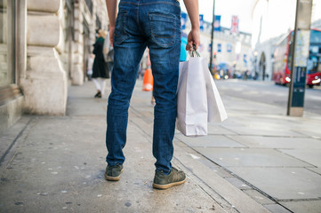 Unrecognizable man with shopping bags in the street, back view