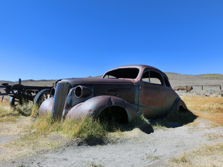 Abandoned rusty metal car in desert sun - landscape color photo