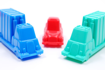 Colorful plastic toy cars of different colors on a white background. Trucks blocked the car. Close up view, selective focus.