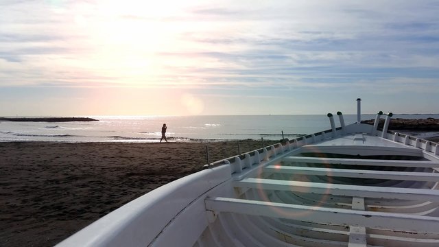 4K Beach at sunset with boat and man walking