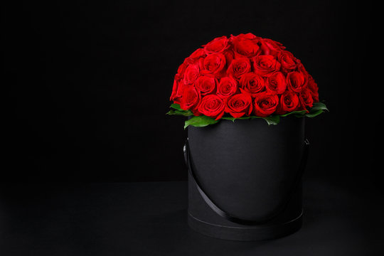 Fototapeta Romantic luxury red roses in a black gift box with space for logo on a black background studio,studio photography,spring is coming,international women's day