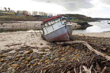 Naklejka na ściany i meble Abandoned and wrecked old fishing boat at the mouth of River Wansbeck, on the coast of Northumberland, England, UK.