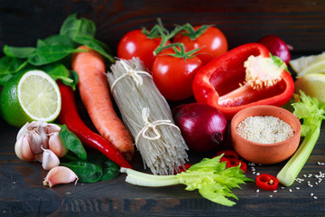 Potato glass noodles and fresh vegetables for cooking Oriental dishes. Bell pepper, chili pepper, tomatoes, lemon, lime, garlic, spinach, carrot, onion, celery, sesame
