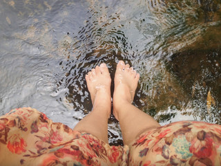 Top view of women leg and feet dip in crystalline stream