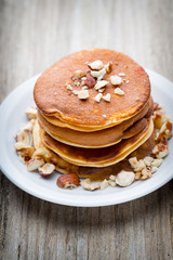 Stack of homemade pancakes with honey on wooden background.