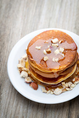 Stack of homemade pancakes with honey on wooden background.