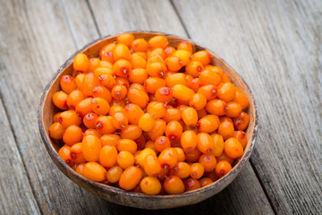 Buckthorn berry basket on wooden background.