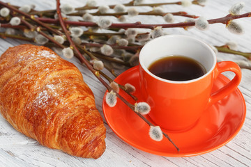 Cup of coffee and croissant with pussy willow