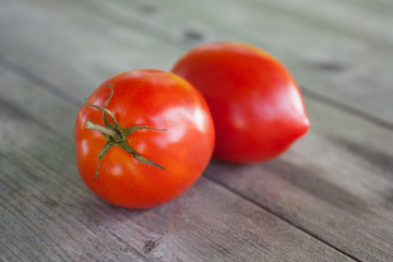 Two ripe red tomatoes on an old wooden table in  country garden in summer day