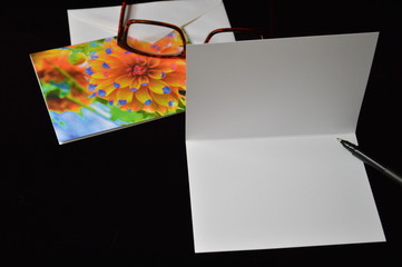 Blank custom notecard with eyeglasses and pen on a black background
