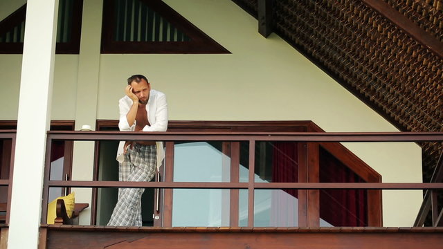 sad, pensive man on the terrace of luxury villa 

