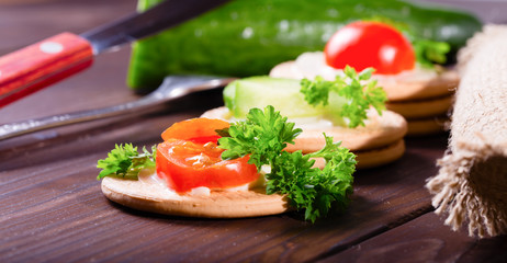 Cheese, tomatoes and greens of parsley on cookies. Nearby tablew