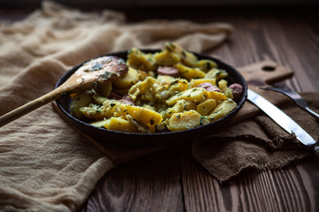 fried potatoes with egg, herbs, sausages, pan, napkin, fork, kni