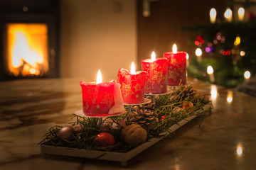 Adventskerzen mit Christbaum und brennendem Kaminfeuer 