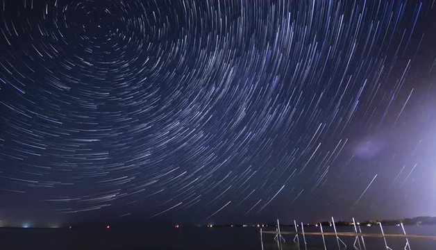 Stars rotating in a whirling mass of vortex moving over cottage pier on lake in summer