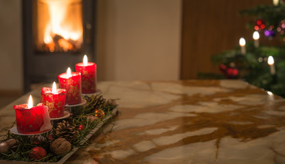 Adventskerzen mit Christbaum und brennendem Kaminfeuer 