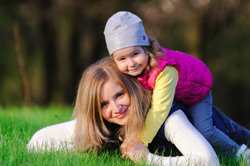 Little girl and her mother hugging outdoors on spring meadow