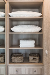 Fototapeta na wymiar white towel and white pillow in wooden wardrobe with basket