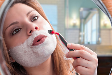 girl in the mirror shaving with razor 
