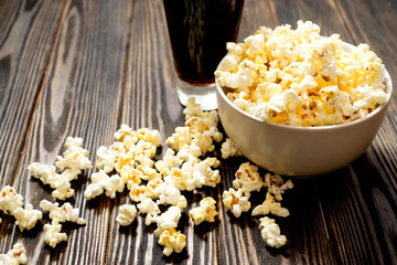 cheese popcorn in the bowl with a glass of cola or beer and potato chips on the wooden background