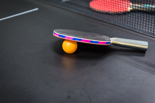 table tennis racket with orange ball