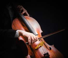 Man playing on cello on dark background