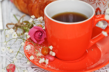 Cup of coffee and croissant with roses