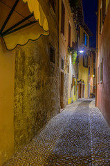Narrow street of old apartment buildings at night in Malcesine, Italy.