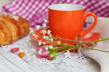 Cup of coffee and croissant with roses