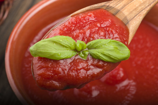 wooden spoon with tomato sauce and basil