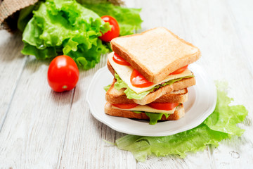 
breakfast or lunch , sandwiches with cheese , sausage , tomato, lettuce and mayonnaise on a wooden background