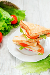 
breakfast or lunch , sandwiches with cheese , sausage , tomato, lettuce and mayonnaise on a wooden background