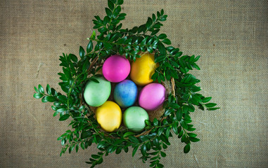 easter eggs in the wicker basket with green branches. top view