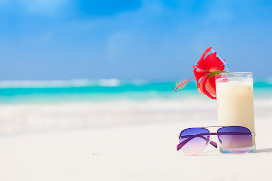 picture of fresh pina colada and sunglasses on tropical beach