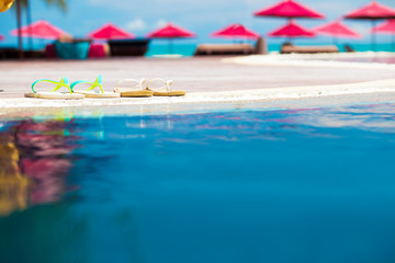 pair of bright flip flops beside blue pool