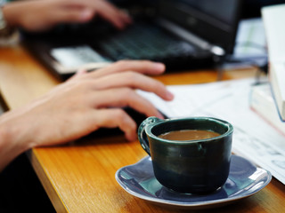human hand holding mouse working with laptop on workplace in office
