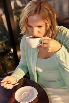 Adult woman sitting in coffee shop for drinking coffee