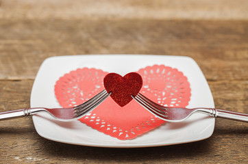 Pair of forks holding red heart during valentines day dinner