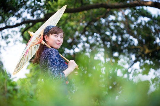 beautiful Asian girl holds umbrella in green tea plantation