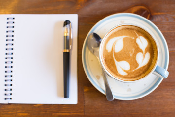 Coffee cup and notebook on table background